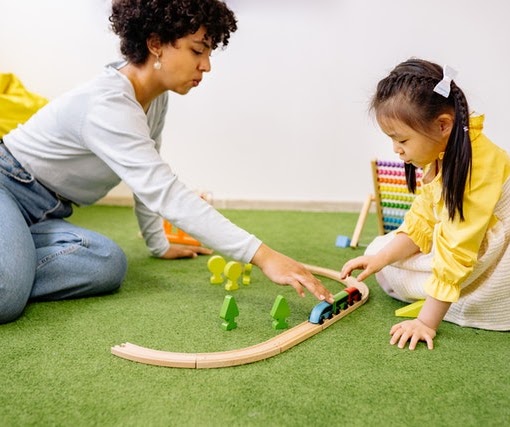 A therapist and child engaged in play-based speech and language therapy with a toy train set